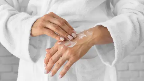 Mujer aplicándose crema en las manos Mujer aplicándose crema en las manos