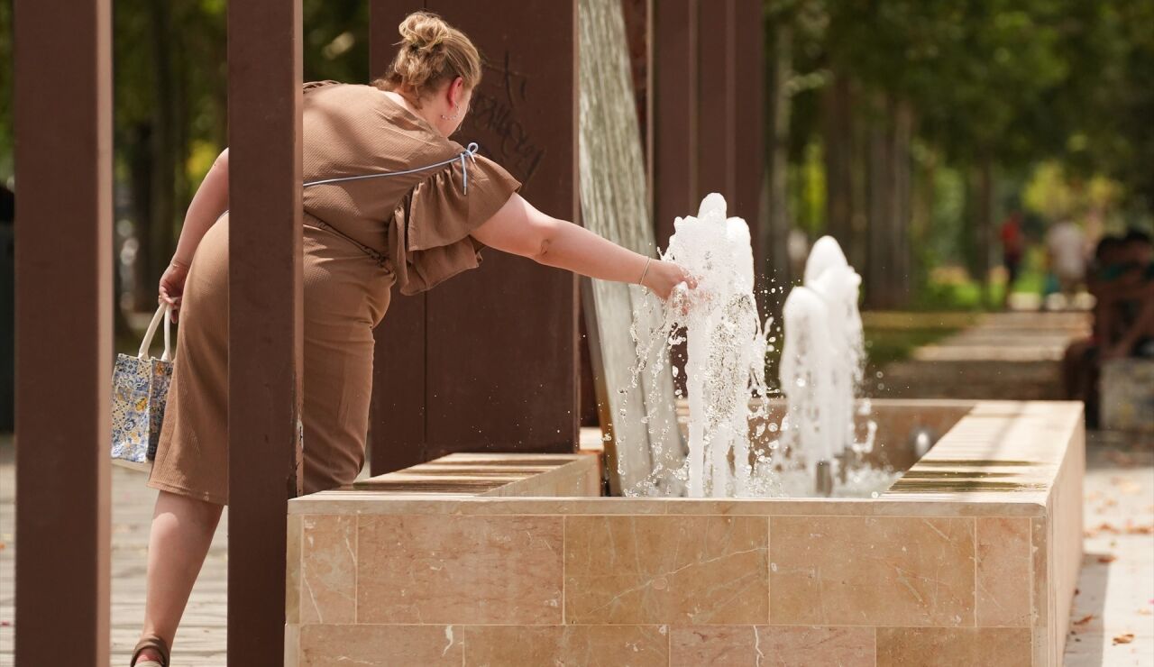 Imagen de una mujer refresc&aacute;ndose en una fuente