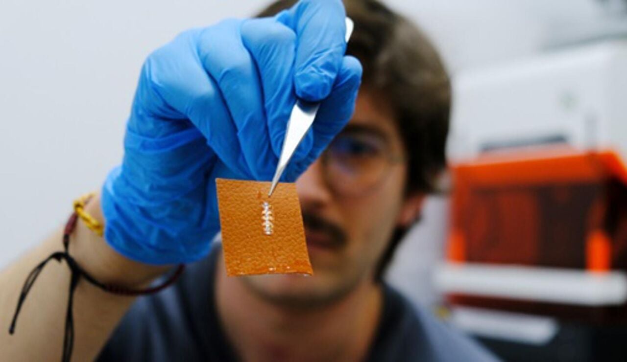 El investigador Yigit Sozen sostiene un chip en un trozo de piel