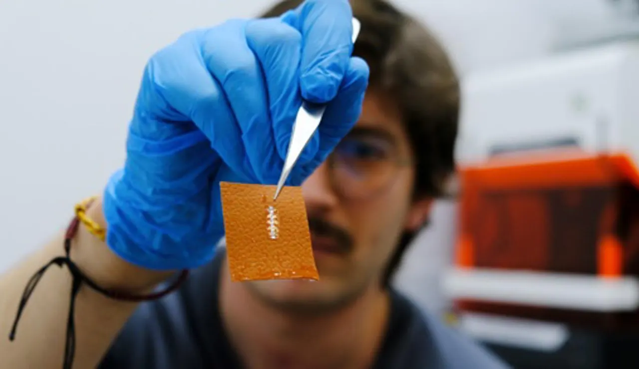 El investigador Yigit Sozen sostiene un chip en un trozo de piel