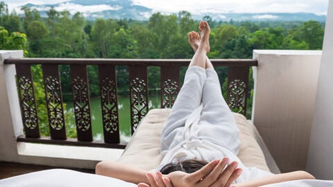 Mujer descansando en la terraza de una habitación de hotel