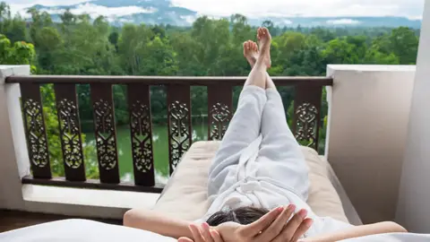Mujer descansando en la terraza de una habitación de hotel Mujer descansando en la terraza de una habitación de hotel