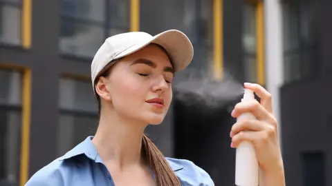 Mujer aplicándose una bruma Mujer aplicándose una bruma