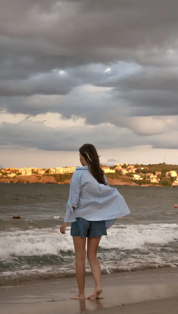Mujer en la playa con vaqueros cortos y camisa ancha Mujer en la playa con vaqueros cortos y camisa ancha
