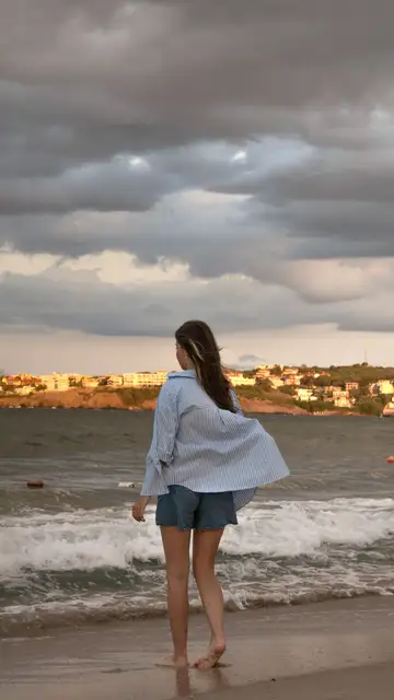 Mujer en la playa con vaqueros cortos y camisa ancha Mujer en la playa con vaqueros cortos y camisa ancha