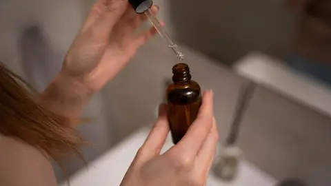 Manos sujetando un bote de sérum Manos sujetando un bote de sérum