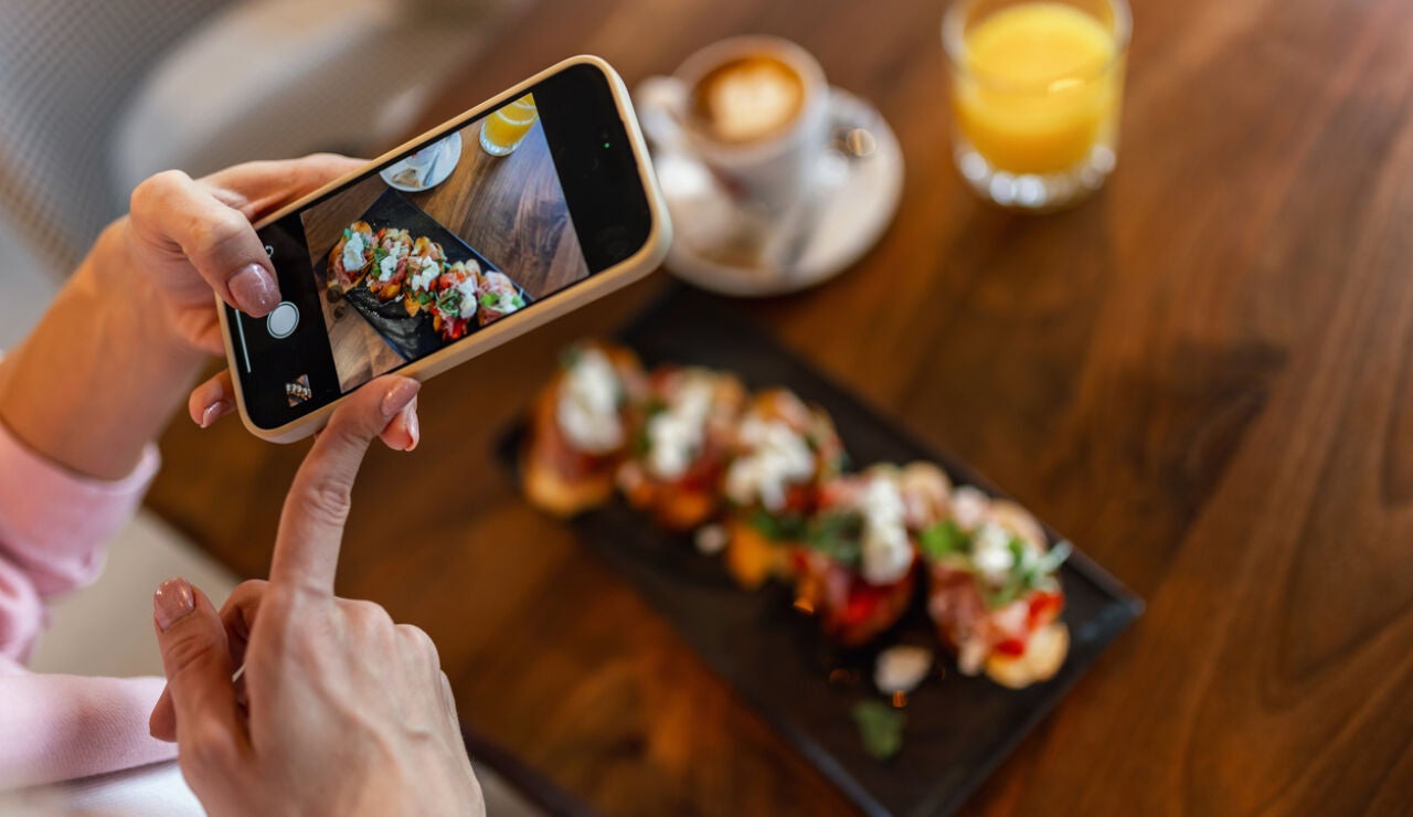 Una joven fotograf&iacute;a su plato en un restaurante