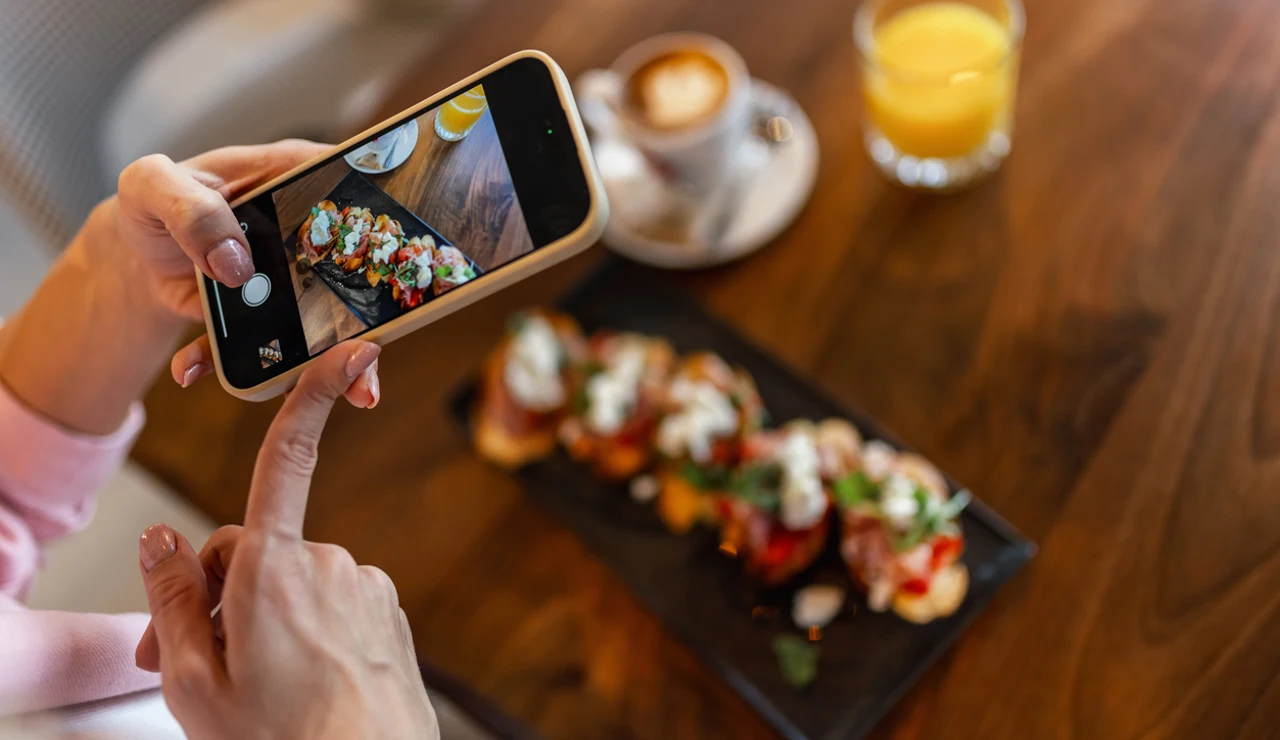 Una joven fotografía su plato en un restaurante