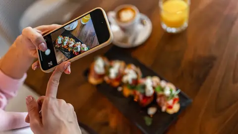 Una joven fotografía su plato en un restaurante Una joven fotografía su plato en un restaurante