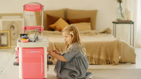 Imagen de una niña jugando con una cocina de juguete Imagen de una niña jugando con una cocina de juguete