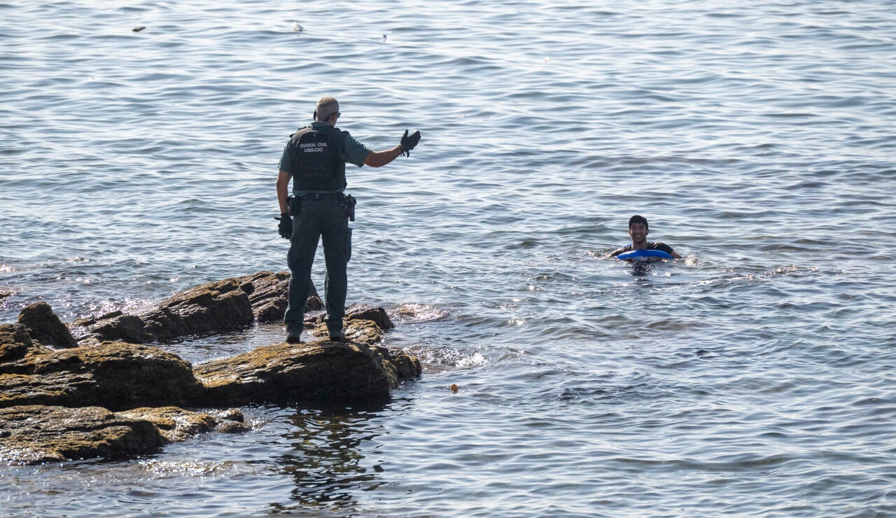 Un guardia civil avisa a una persona que nada en el mar, a 2 de agosto de 2026, en Ceuta