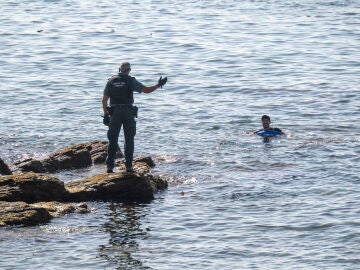 Un guardia civil avisa a una persona que nada en el mar, a 2 de agosto de 2026, en Ceuta