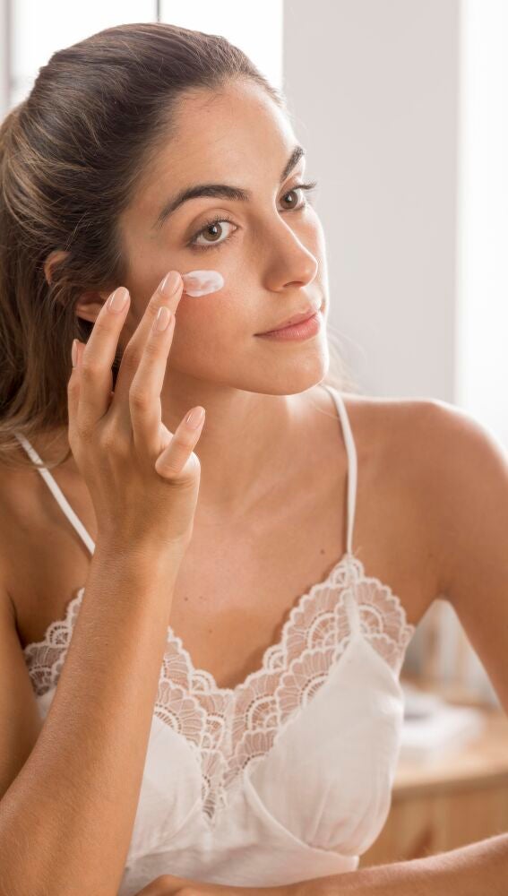 Mujer aplicándose protección solar en el rostro
