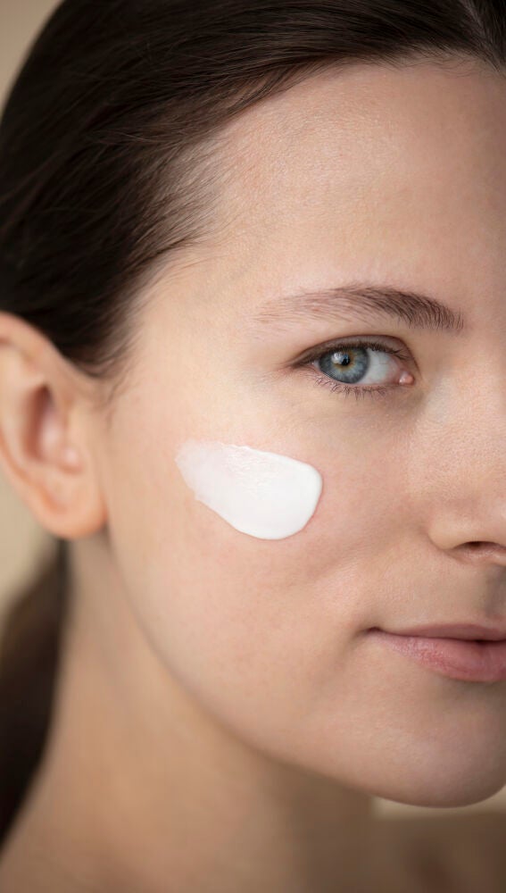 Mujer aplicándose protección solar en el rostro