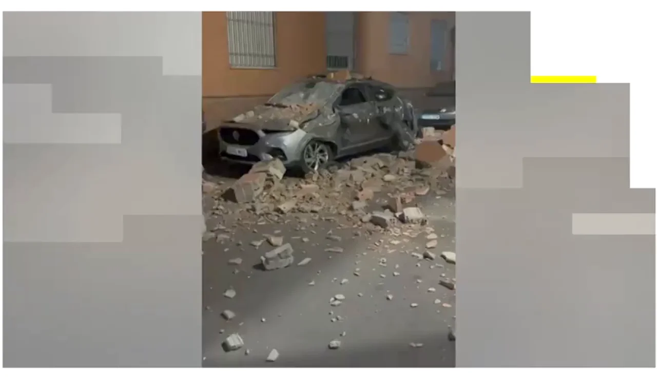 Un coche destrozado tras caer sobre él restos de un edificio por el terremoto de Granada.