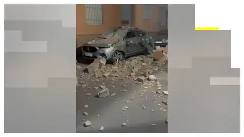 Un coche destrozado tras caer sobre él restos de un edificio por el terremoto de Granada. Vídeo: Las impactantes imágenes de los daños del terremoto de magnitud 5 en Granada