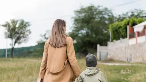 Mujer llevando a su hijo a la escuela Mujer llevando a su hijo a la escuela