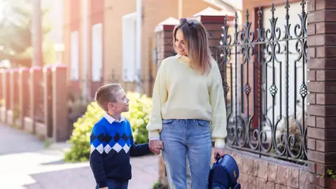 Mujer llevando a su hijo a la escuela Mujer llevando a su hijo a la escuela