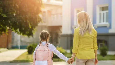 Mujer llevando a su hija a la escuela Mujer llevando a su hija a la escuela