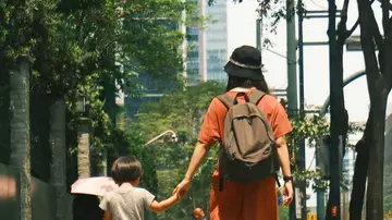 Mujer llevando a su hijo a la escuela Mujer llevando a su hijo a la escuela