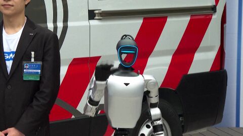 Un robot posa junto a la ambulancia de robots humanoides japonesa.