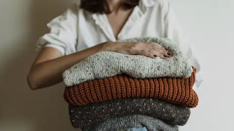 Una mujer sujetando cuatro jerséis Una mujer sujetando cuatro jerséis