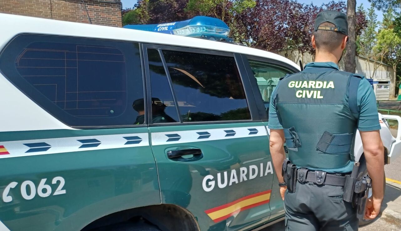 Un agente y un coche de la Guardia Civil.
