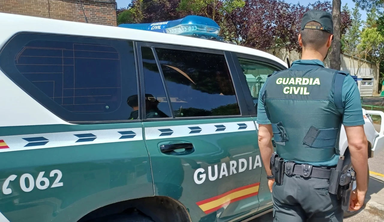 Un agente y un coche de la Guardia Civil.