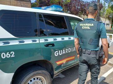 Un agente y un coche de la Guardia Civil.