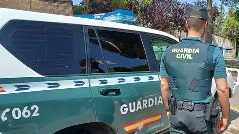 Un agente y un coche de la Guardia Civil. Un agente y un coche de la Guardia Civil.