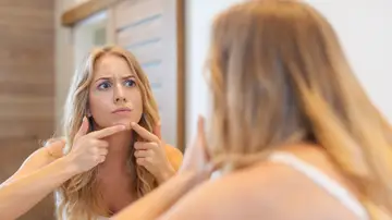 Mujer tocándose un grano Mujer tocándose un grano