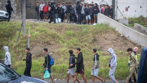 Agentes de la Polic&iacute;a Nacional intervienen durante el proceso de desalojo del embolsamiento de migrantes en la playa de El Trampol&iacute;n, a 4 de octubre de 2026, en Ceuta (Espa&ntilde;a). La Polic&iacute;a Nacional escolta los autobuses llenos de personas migrantes desalojadas de la playa del Trampol&iacute;n hacia la zona de la frontera del Tarajal, donde unos optan por quedarse en el Centro de Atenci&oacute;n Temporal para Extranjeros (CATE) al objeto de ser filiados y posteriormente acogidos y otros prefieren regresar a ...