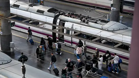 Varios pasajeros pasan ante un AVE en la Estación de Atocha Varios pasajeros pasan ante un AVE en la Estación de Atocha