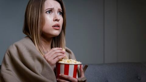 Mujer con un bote de palomitas viendo una película de miedo