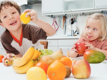 Dos niños comiendo fruta