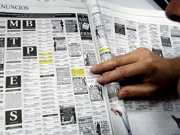 Un hombre lee los anuncios por palabras de un periódico Un hombre lee los anuncios por palabras de un periódico