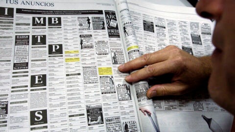 Un hombre lee los anuncios por palabras de un peri&oacute;dico