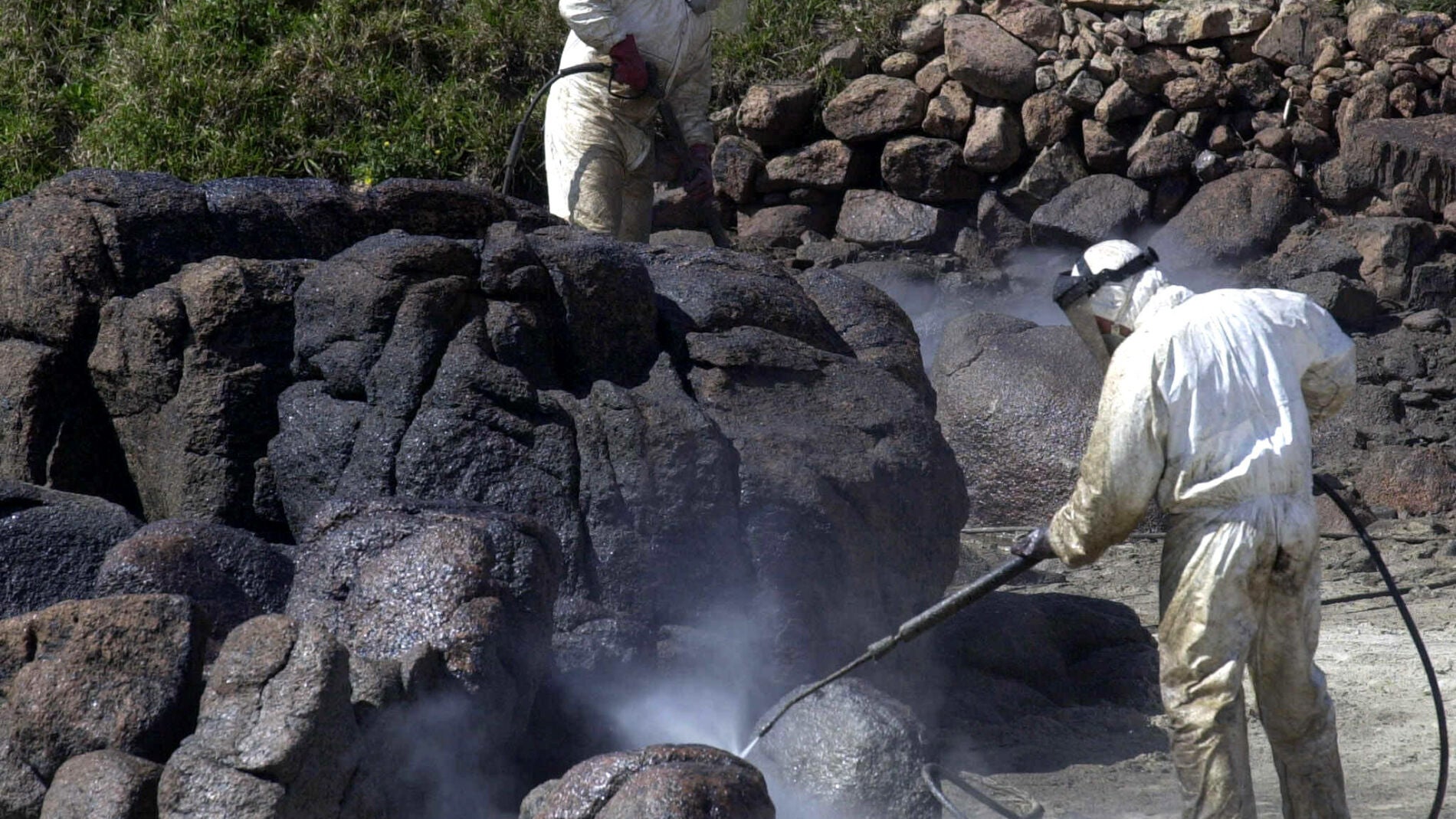 Unos operarios limpian la marea negra del Prestige