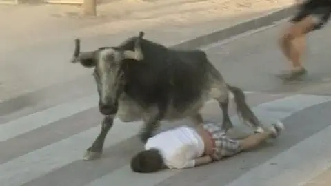 Un joven tumbado en el suelo al paso de un toro Un joven tumbado en el suelo al paso de un toro