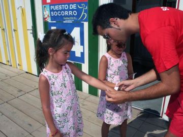 Un socorrista pone las pulseras a dos niñas