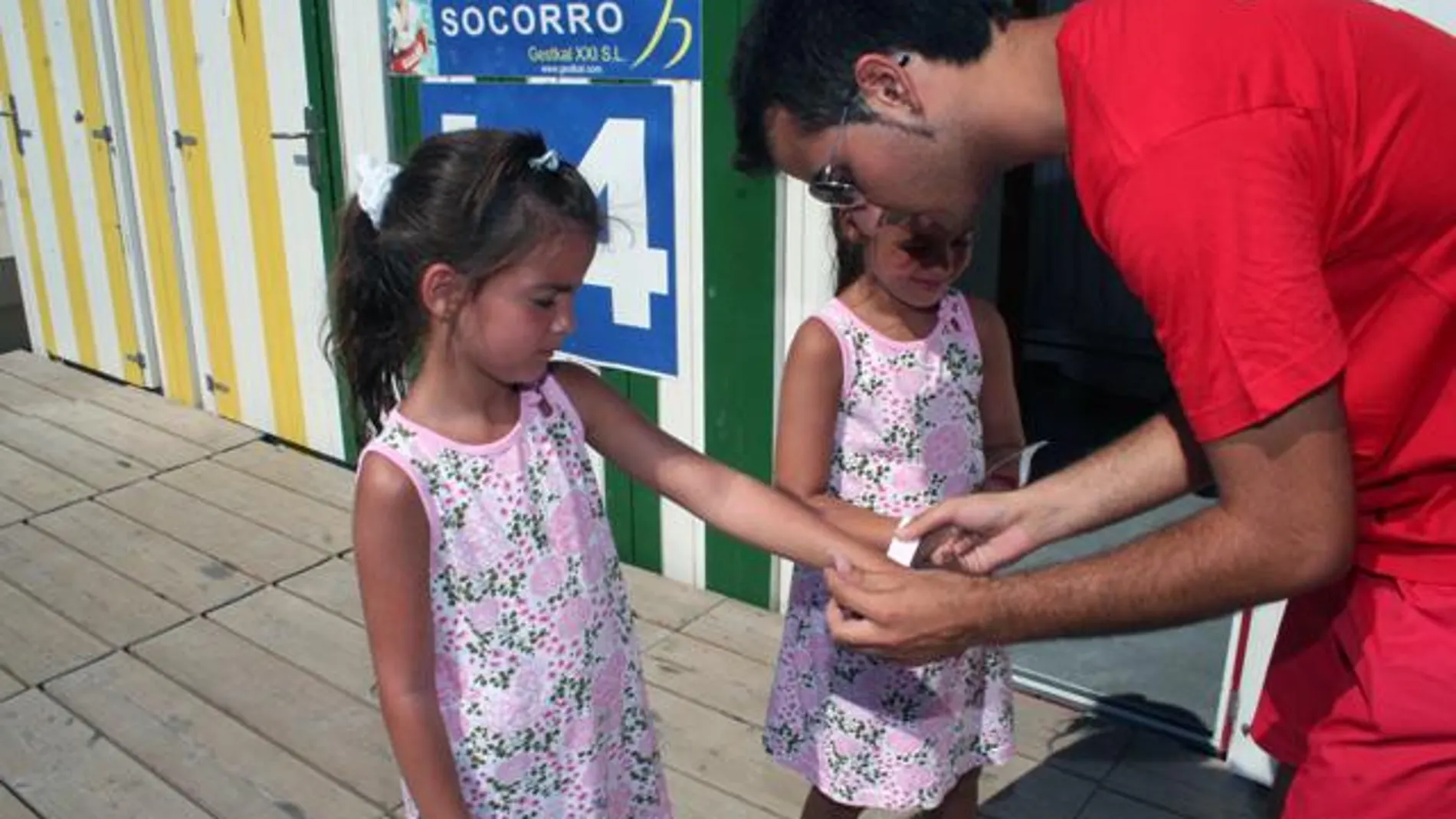 Un socorrista pone las pulseras a dos niñas Un socorrista pone las pulseras a dos niñas