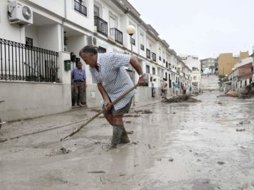 Un vecino fregando el barro de la riada