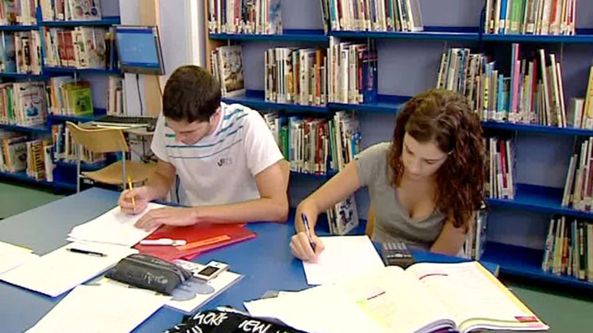 Dos jóvenes estudian en la biblioteca Dos jóvenes estudian en la biblioteca