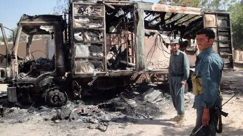 Policías afganos hacen guardia junto a un camión quemado Policías afganos hacen guardia junto a un camión quemado
