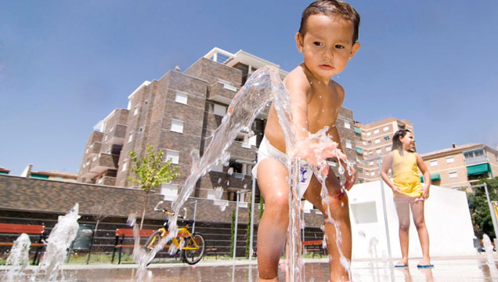 Un bebé se refresca en una fuente