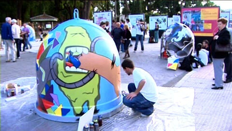 Un joven hace un graffiti en un contenedor