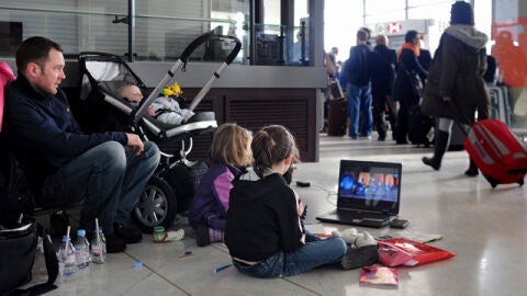 Dos ni&ntilde;os esperan junto a sus padres en el aeropuerto Charles de Gaulle, Par&iacute;s