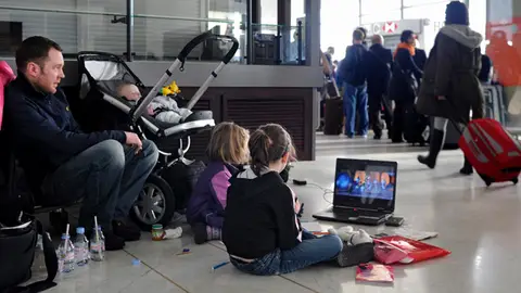 Dos niños esperan junto a sus padres en el aeropuerto Charles de Gaulle, París Dos niños esperan junto a sus padres en el aeropuerto Charles de Gaulle, París