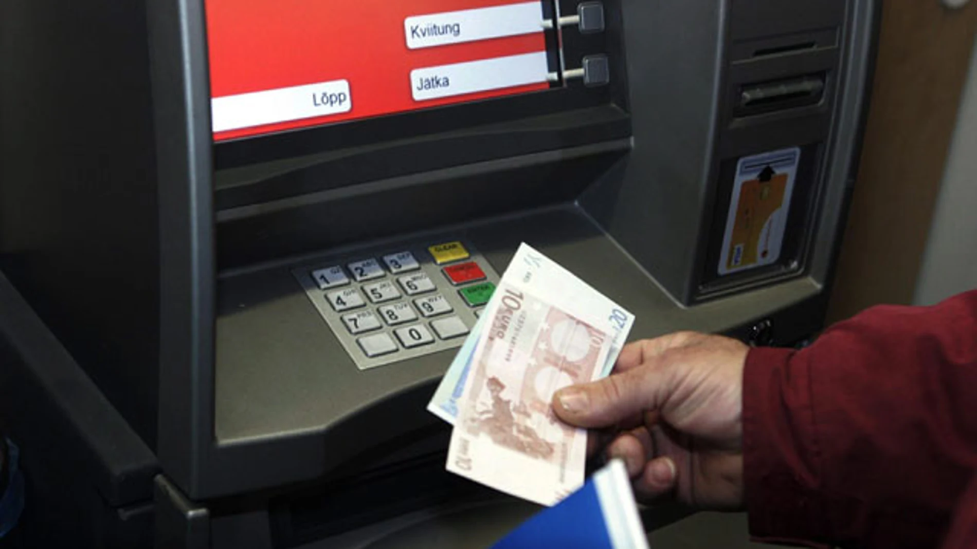 Un hombre saca billetes de euros en Tallín, Estonia Un hombre saca billetes de euros en Tallín, Estonia