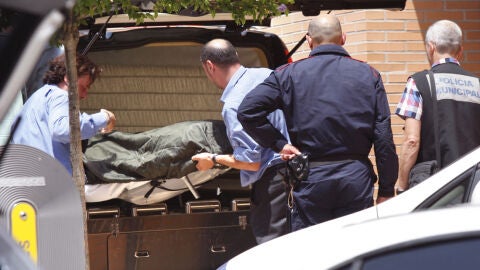 Empleados de la funeraria trasladan el cuerpo de la mujer y su hijo que han sido hallados muertos